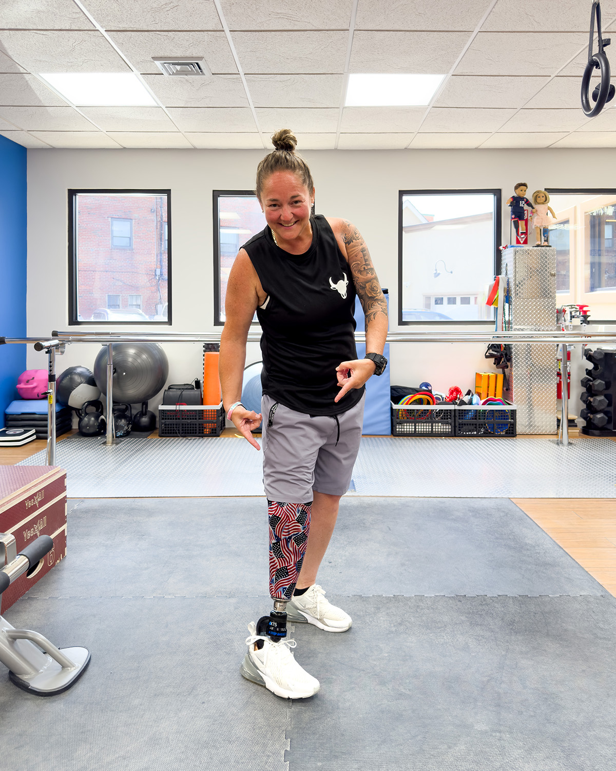 Below knee amputee pointing at custom prosthetic art, pattern of american flags
